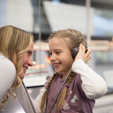 Mädchen und Frau hören Informationen mit einem Kopfhörer an