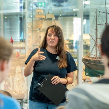 Museumspädagogin spricht vor einer Gruppe in der Ausstellung Schifffahrt
