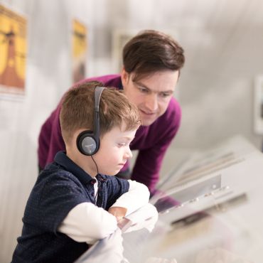 Junge und Vater mit Kopfhörern auf der Empore in der Luftfahrtausstellung