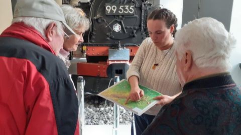 Führung mit Menschen mit Demenz schauen auf eine Landkarte in der Ausstellung Schienenverkehr