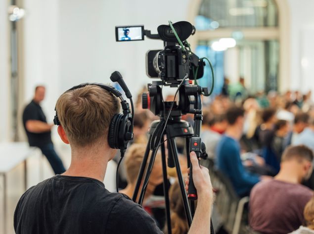 Ein Kameramann filmt viele Menschen im Publikum