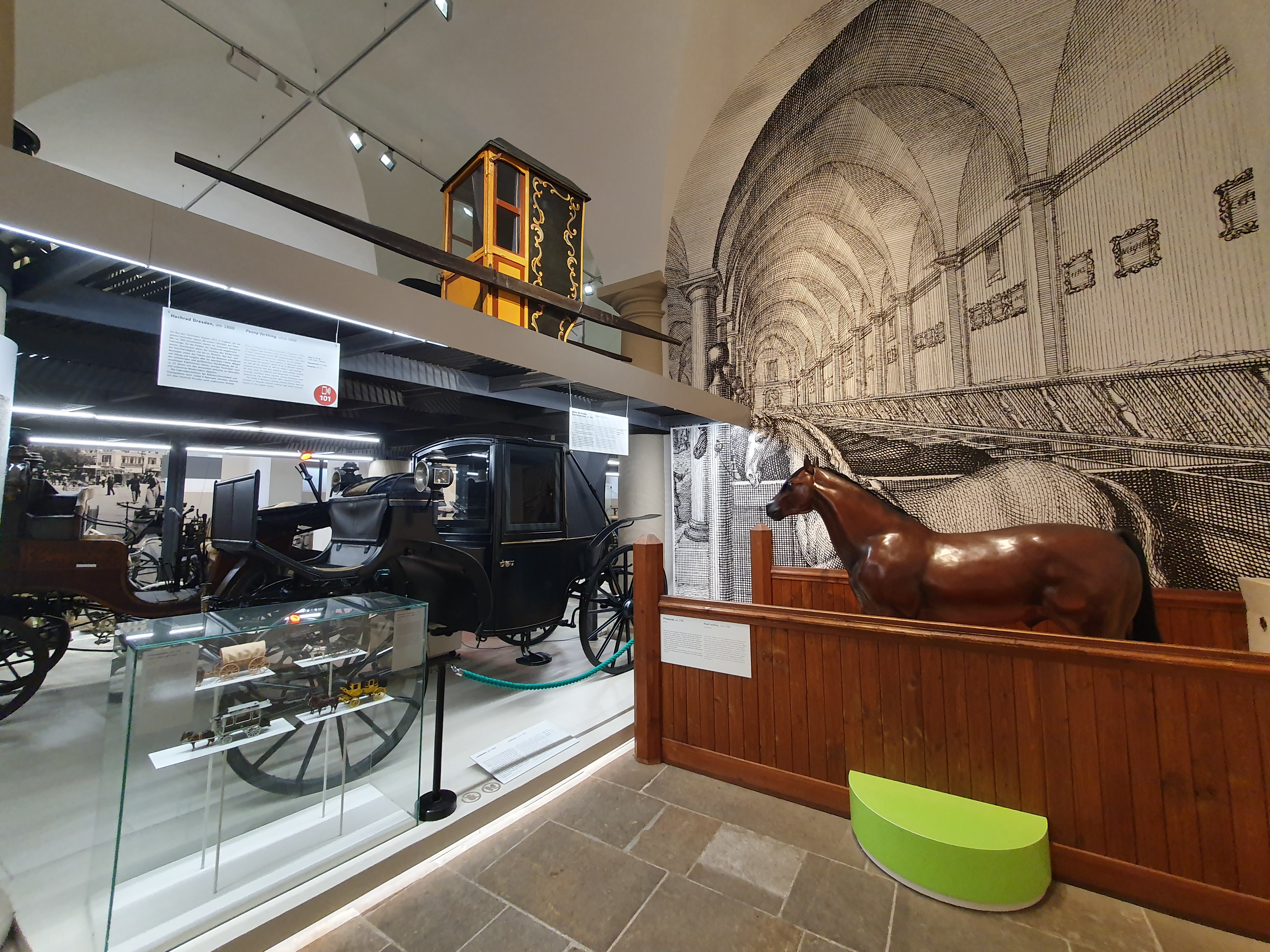 Pferd vor der historischen Kullisse des Verkehrsmuseums als Stall sowie eine elegante schwarze Kutsche