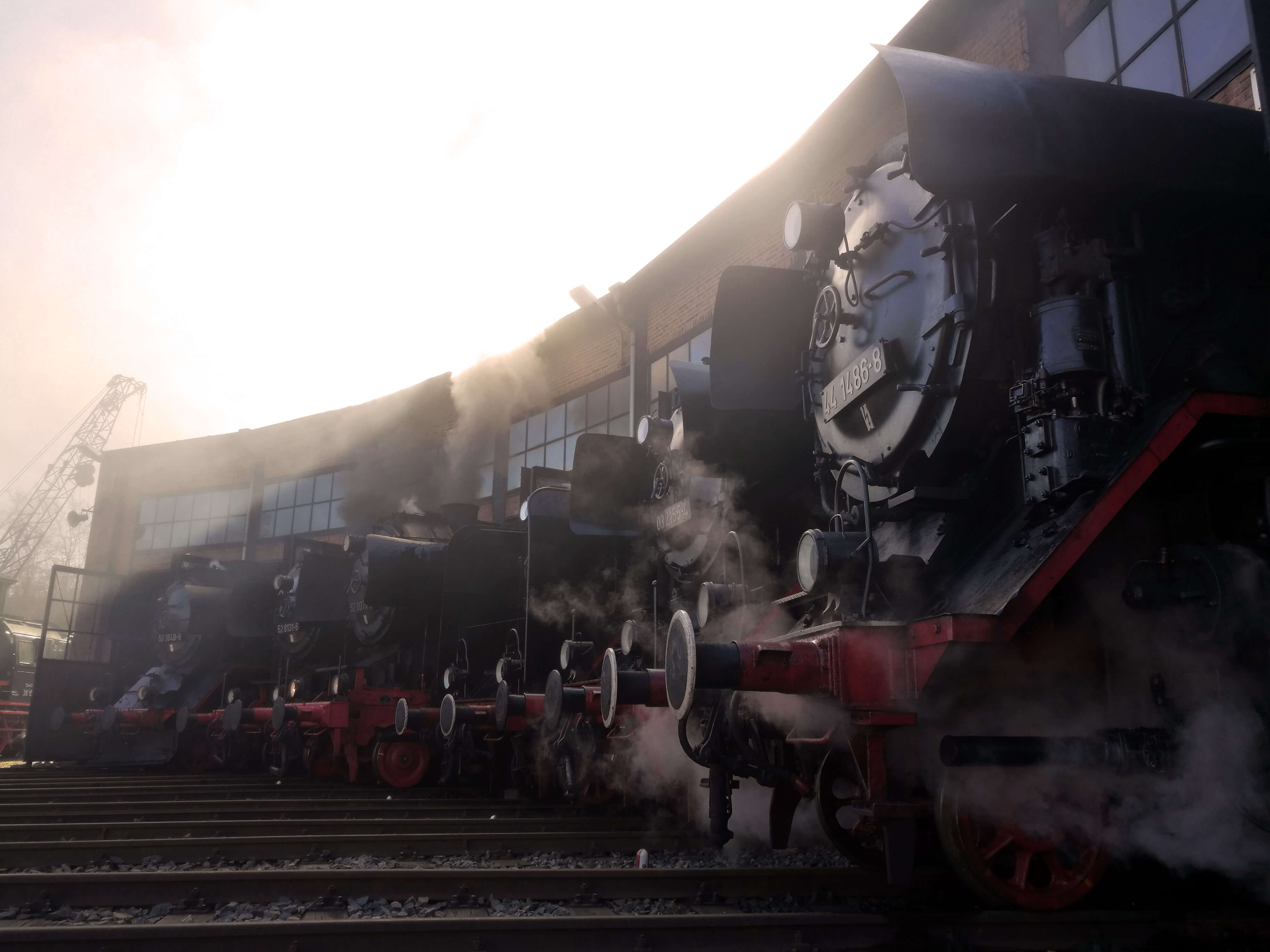 Rauchende Dampflokomotiven vor einem Bahnhof